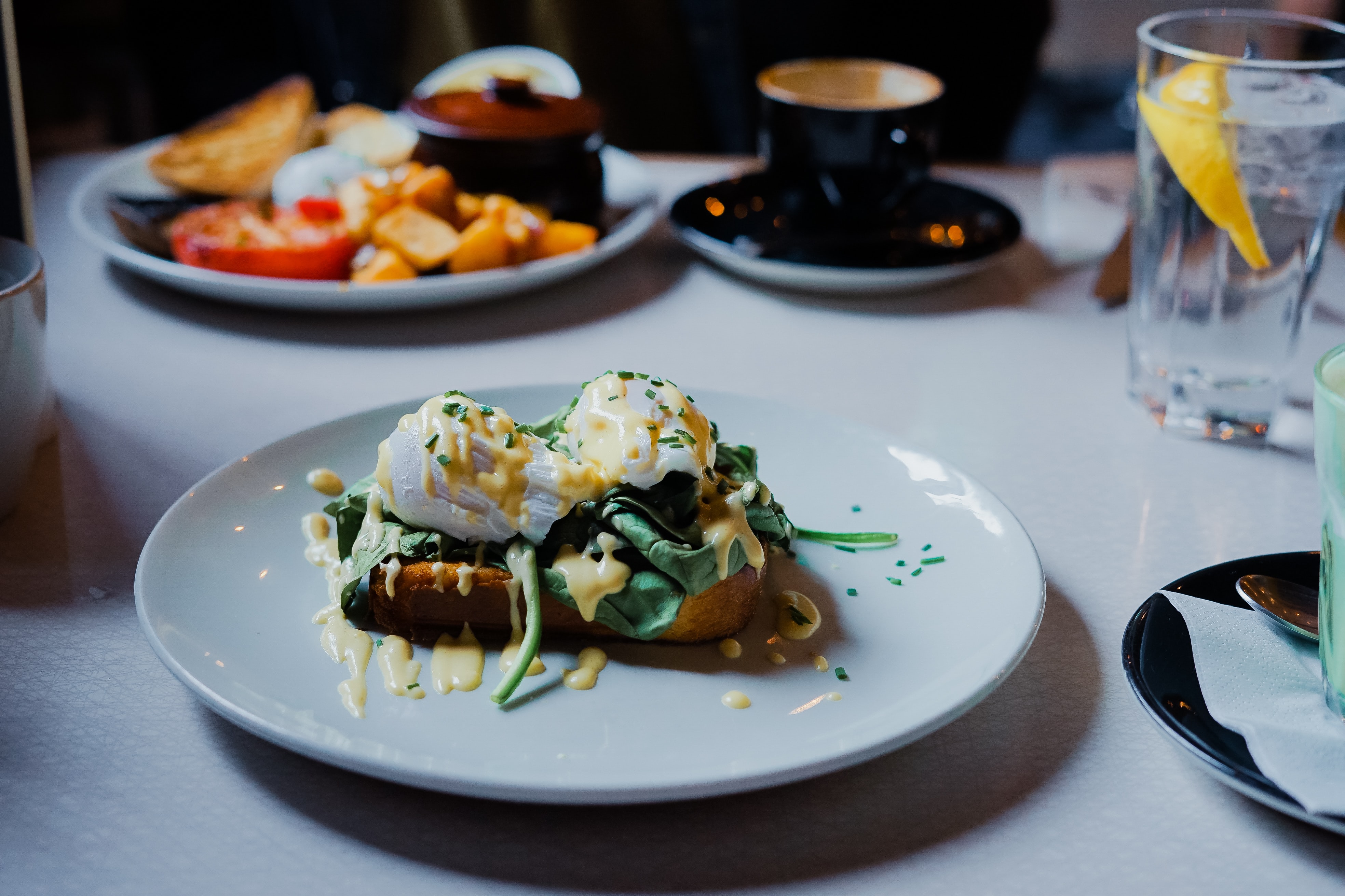 tartine épinards et oeufs mollets recouverte de sauce servie dans une assiette blanche