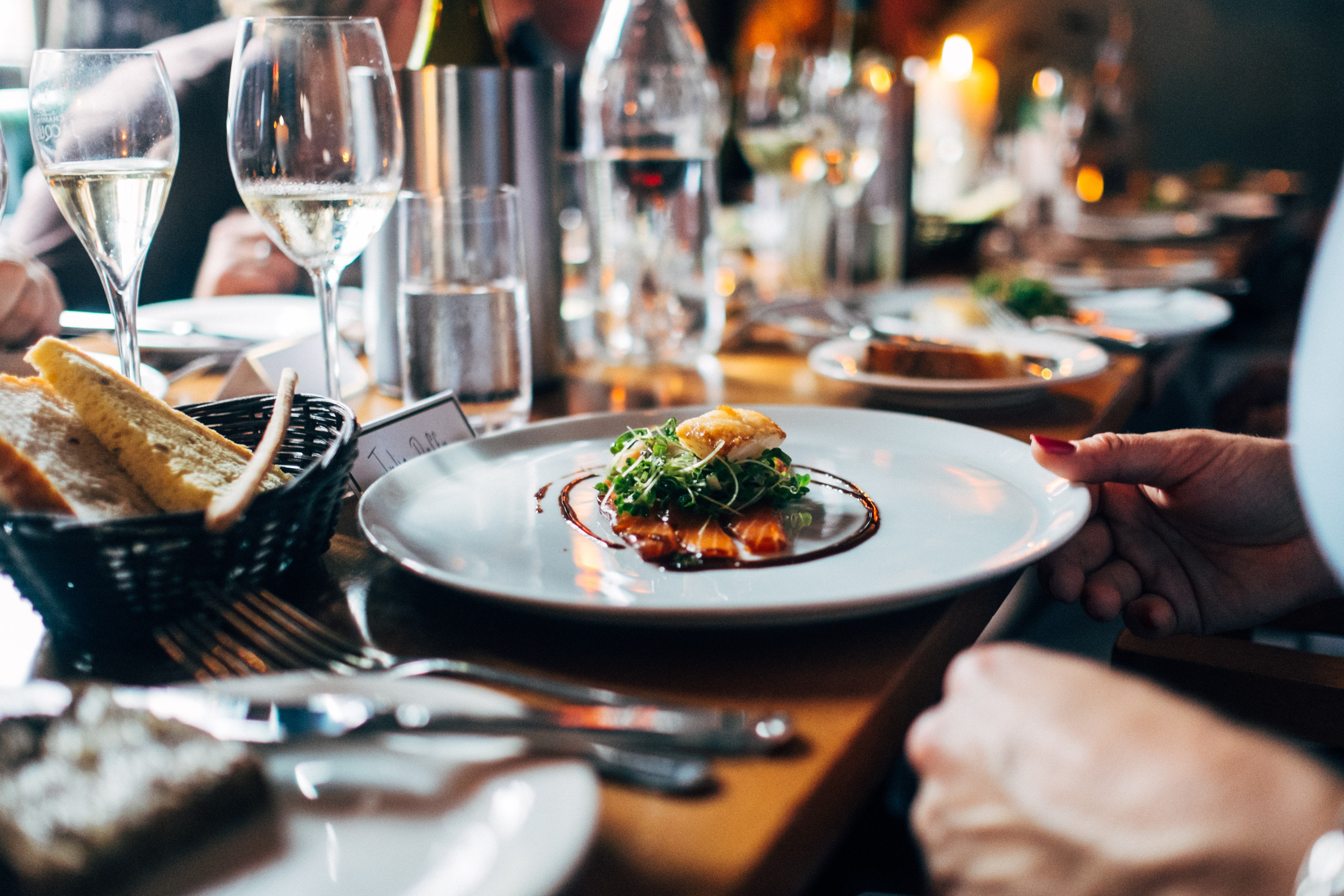 table au restaurant avec un plat de poisson sur lit de salade servi dans une assiette blanche